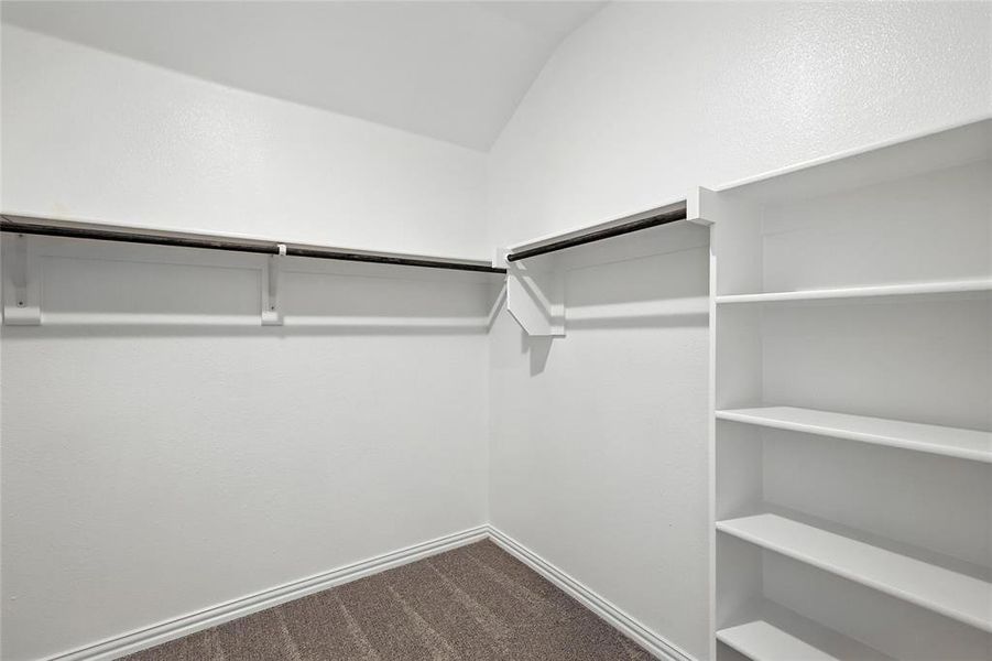 Spacious closet featuring dark colored carpet and vaulted ceiling Spacious closet featuring dark colored carpet and vaulted ceiling