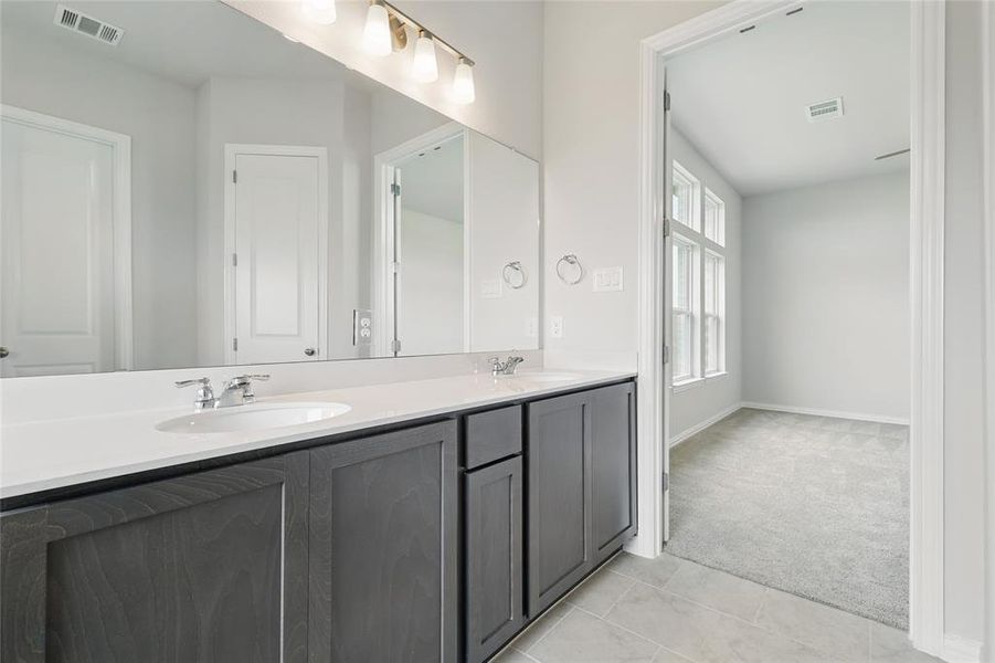 Full bathroom featuring double vanity, tile patterned floors, and baseboards Full bathroom featuring double vanity, tile patterned floors, and baseboards