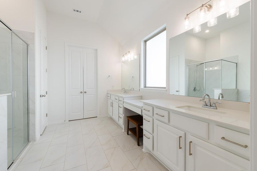 Bathroom with a shower stall, two vanities, and lofted ceiling