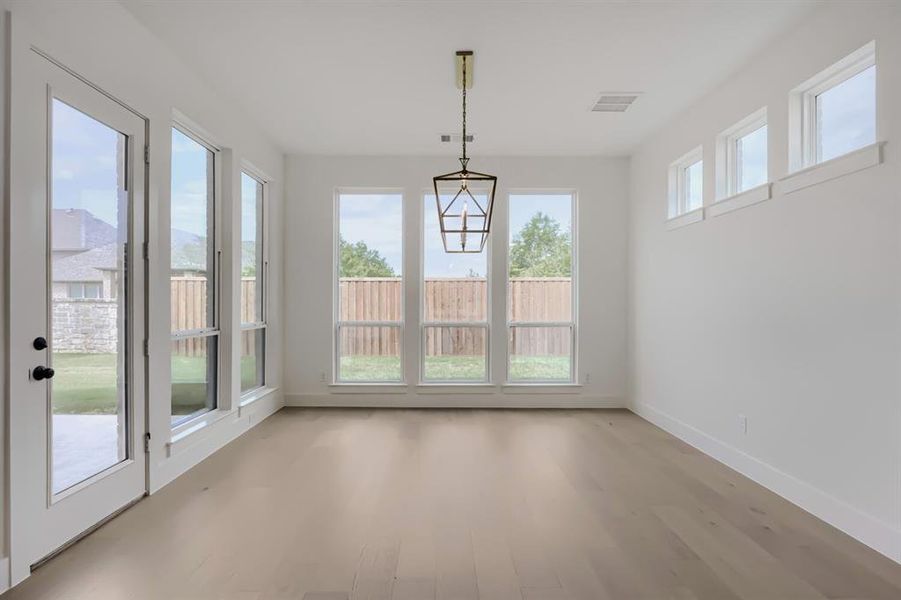 Room with wood-finish flooring, white walls, and multiple windows Room with wood-finish flooring, white walls, and multiple windows