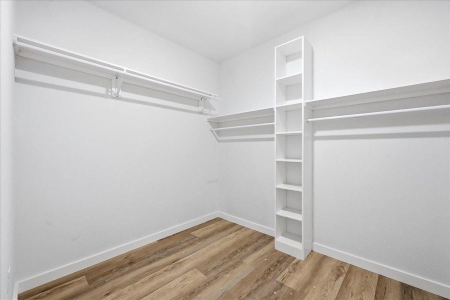Huge walk-in primary closet featuring custom built-in shelving and ample hanging space. Huge walk-in primary closet featuring custom built-in shelving and ample hanging space.