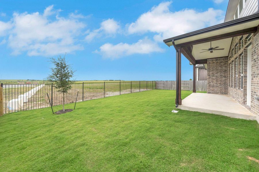 Fenced backyard featuring a ceiling fan, a patio area, and a rural view Fenced backyard featuring a ceiling fan, a patio area, and a rural view