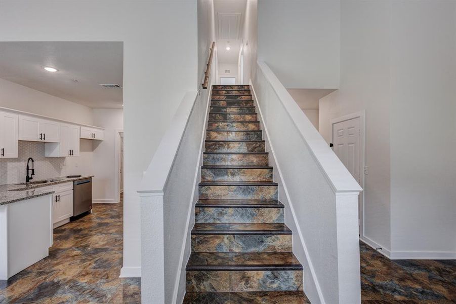 Stairs featuring dark tile patterned floors and sink