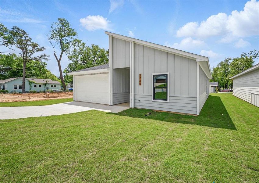 View of front facade featuring board and batten siding, a front lawn, and a garage