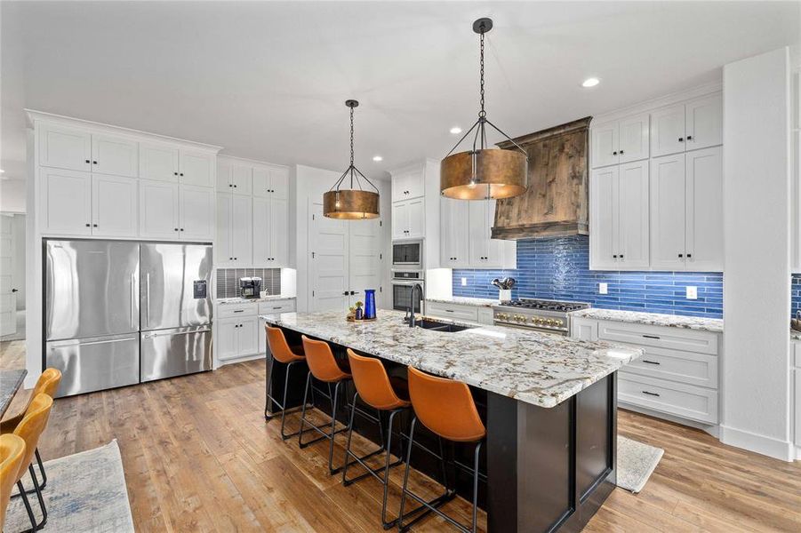 Kitchen featuring white cabinetry, a kitchen island with sink, backsplash, a breakfast bar area, and recessed lighting