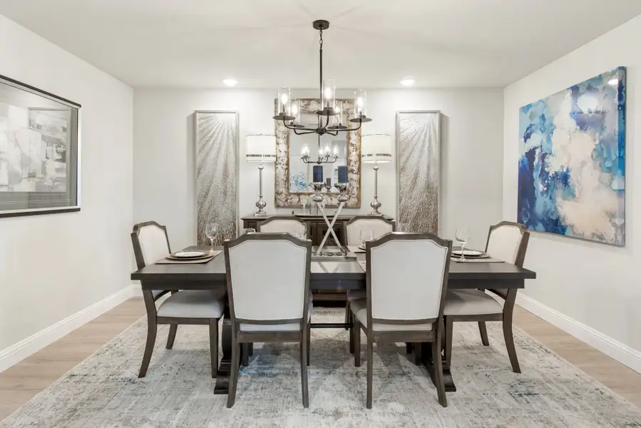 Formal dining room with dark wood table, six upholstered chairs, chandelier, and wall art on light hardwood floors
