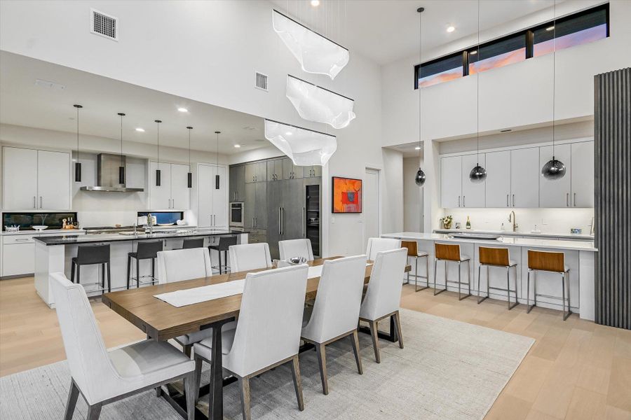 Dining space featuring a high ceiling, light wood-style floors, and recessed lighting Dining space featuring a high ceiling, light wood-style floors, and recessed lighting