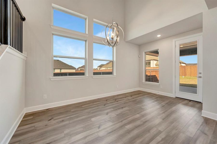 Unfurnished dining area with a high ceiling, a chandelier, and wood finished floors
