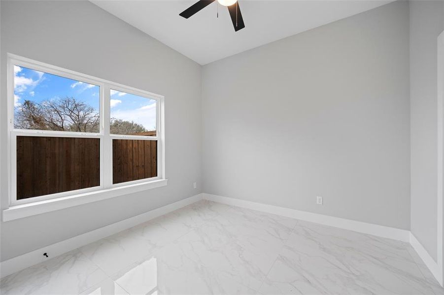 Empty room featuring a ceiling fan, baseboards, and marble finish floor