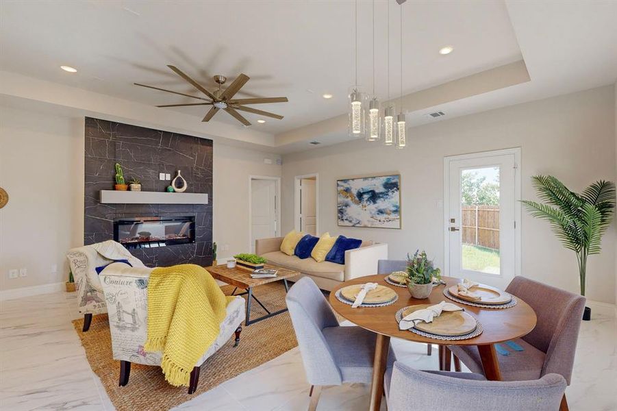 Living room with a raised ceiling, ceiling fan, and a tiled fireplace