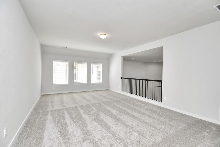 Come upstairs and relish a day of relaxation in this loft area! Ideal as an additional living space or game room, it boasts plush carpeting, high ceilings, custom paint, and windows that flood the area with abundant natural light. Sample photo of completed home with similar floor plan. Actual colors and selections may vary.
