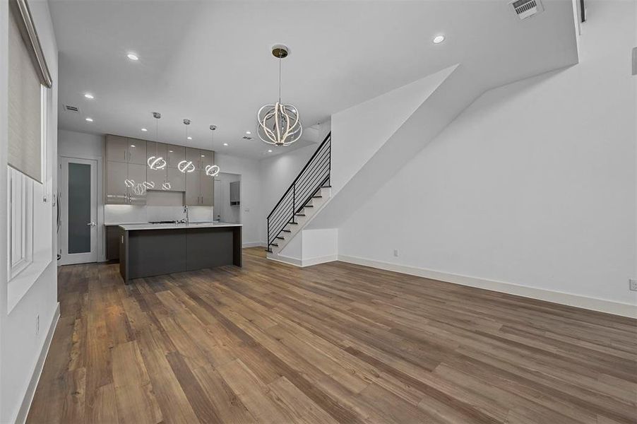 Kitchen with an inviting chandelier, pendant lighting, a center island with sink, sink, and dark hardwood / wood-style floors