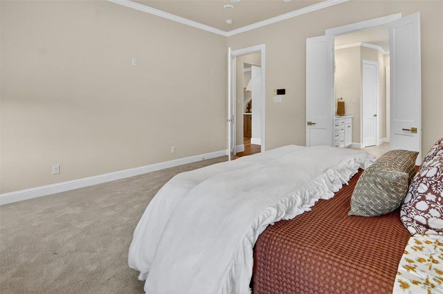 Bedroom featuring ornamental molding, light colored carpet, and connected bathroom