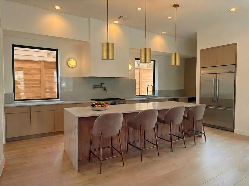 Kitchen- Chef's kitchen with custom cabinetry, waterfall island, Jenair appliance package, and brushed brass pendant lighting. (Rendering)