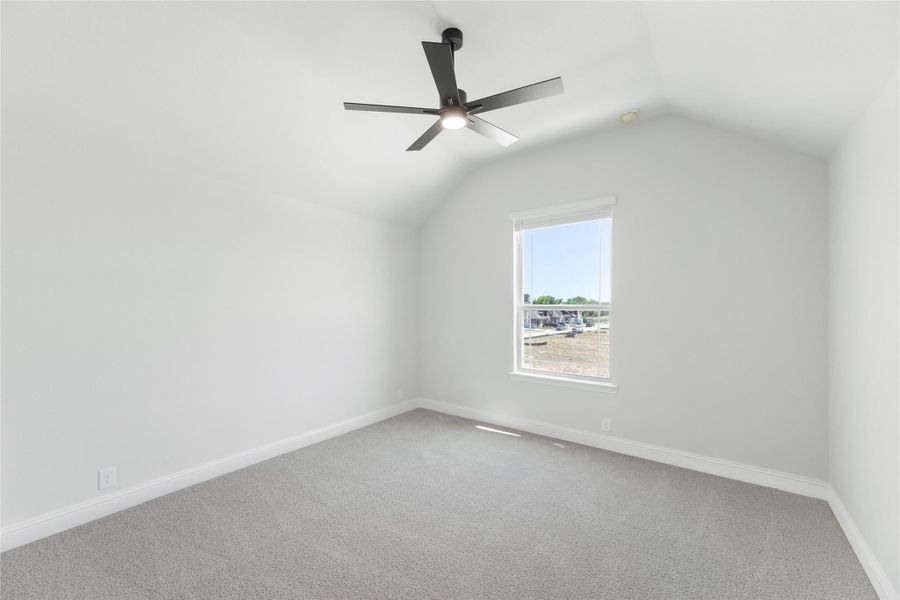 Empty bedroom with vaulted ceiling, black ceiling fan, gray carpet, and single window Empty bedroom with vaulted ceiling, black ceiling fan, gray carpet, and single window