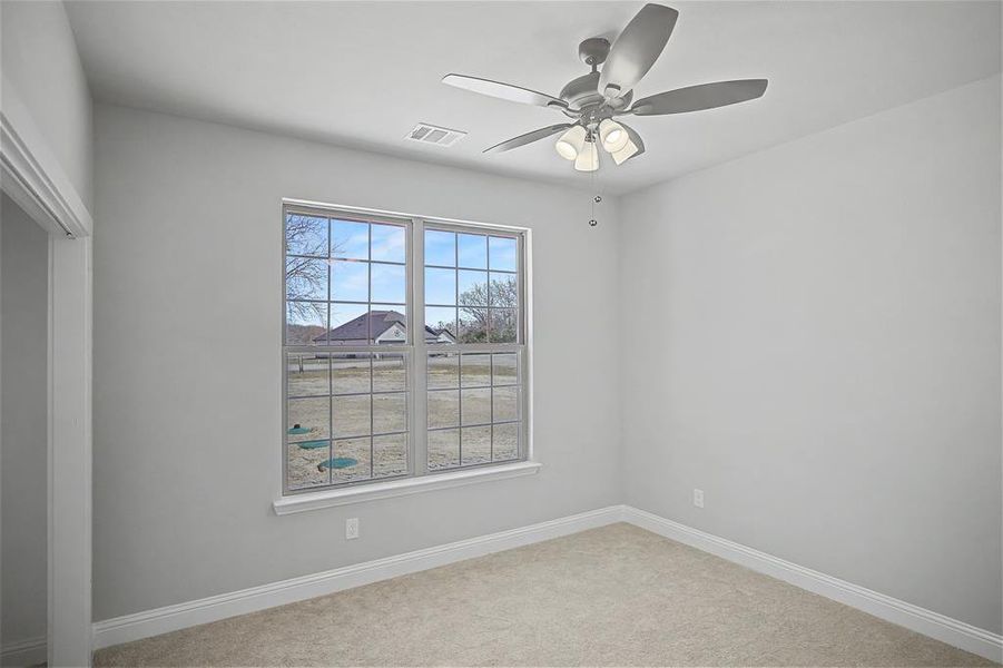Spare room featuring a ceiling fan and light carpet