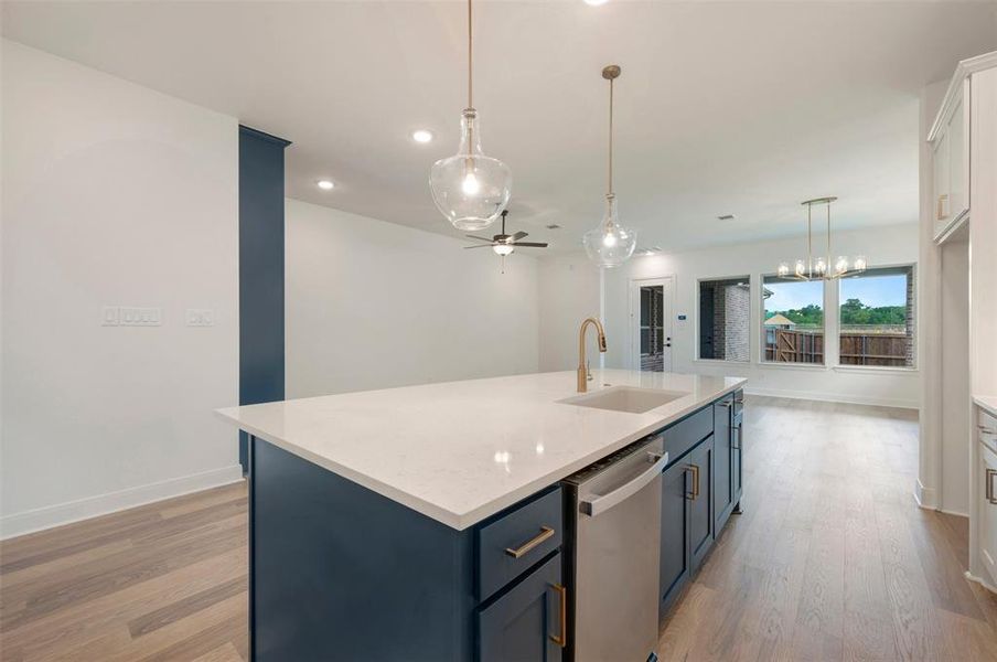 The kitchen features a large island with a white countertop and dark cabinetry, equipped with a sink and a gold-toned faucet