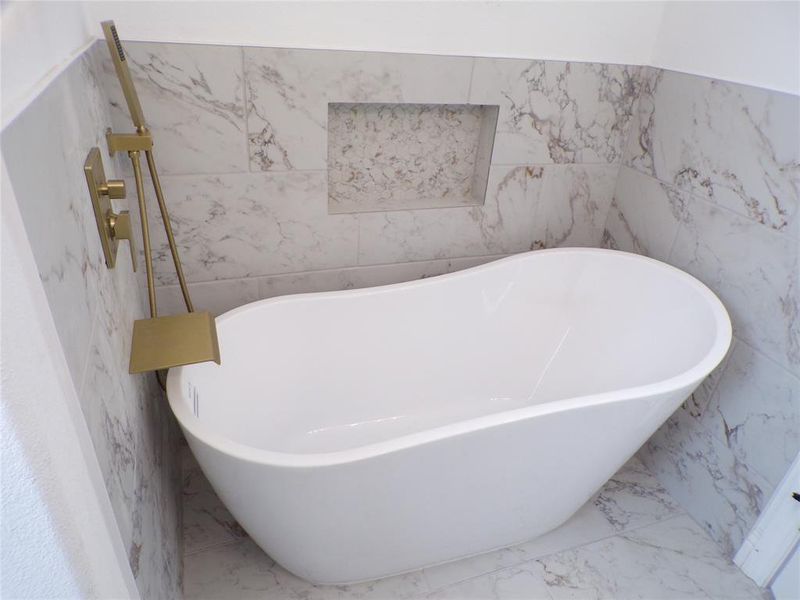 Bathroom featuring a bathing tub, tile walls, and tile patterned flooring