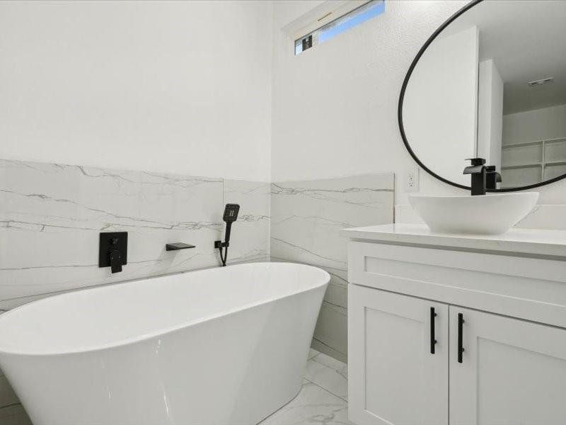 Bathroom featuring a tub to relax in, vanity, tile walls, and tile patterned flooring