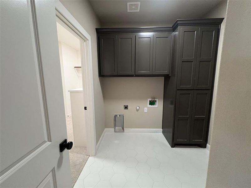 Laundry room with gas dryer hookup, hookup for an electric dryer, hookup for a washing machine, light tile patterned floors, and cabinet space
