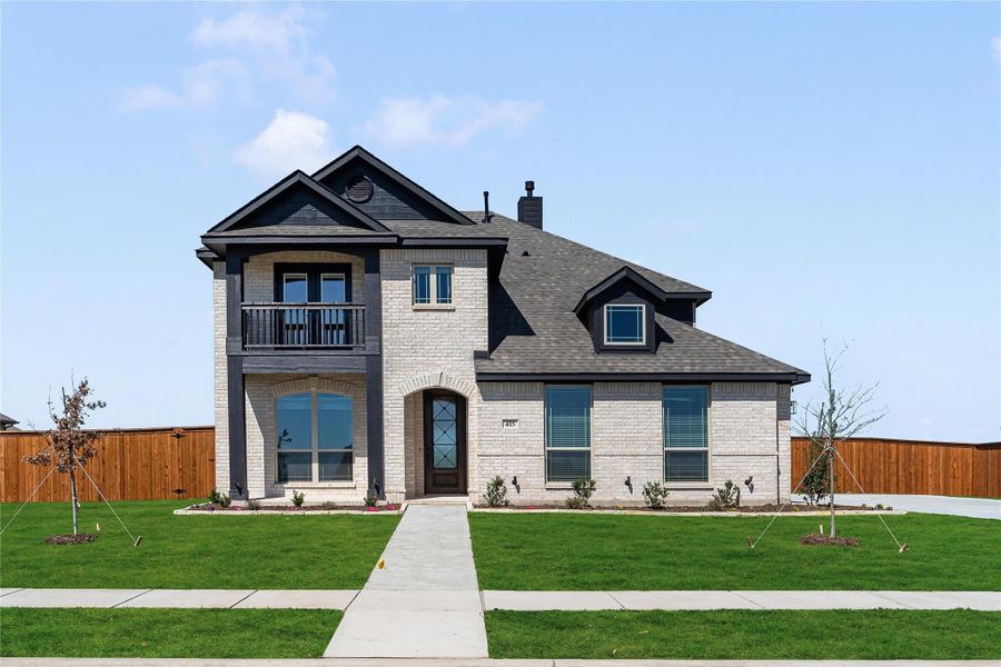 Two-story brick home with arched entry, second-floor balcony, dark roof, and manicured front lawn Two-story brick home with arched entry, second-floor balcony, dark roof, and manicured front lawn