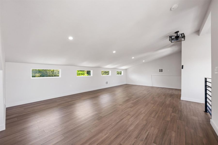 Unfurnished living room with recessed lighting, vaulted ceiling, and dark wood finished floors
