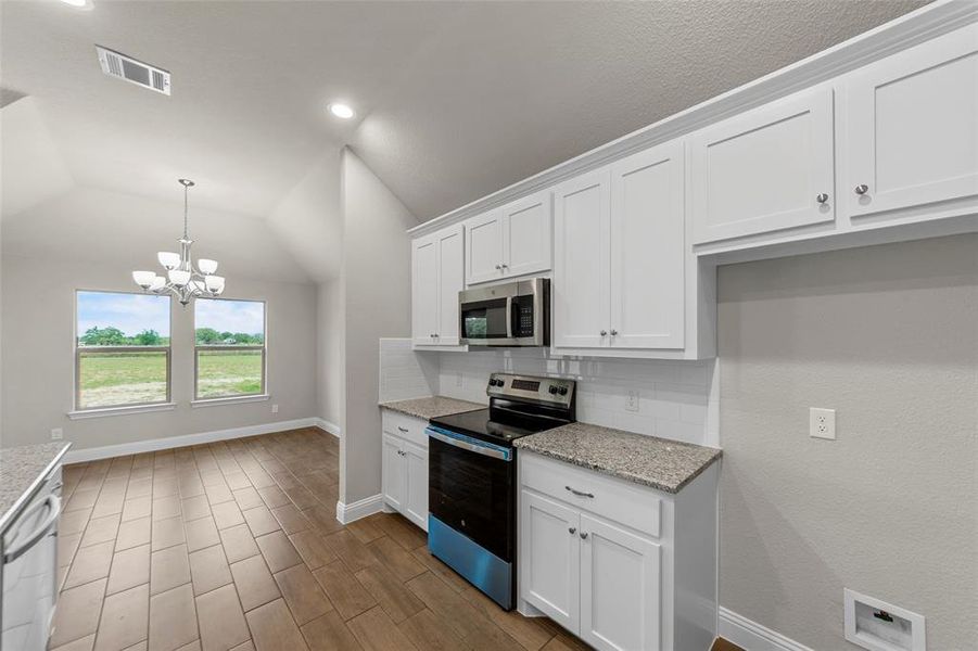 Kitchen and dining area featuring white cabinetry, stainless steel appliances, granite countertops, and a white subway tile backsplash