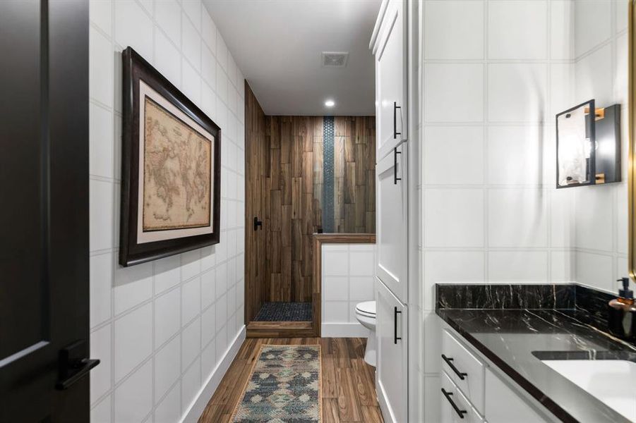 Bathroom featuring tile walls, a shower stall, dark wood finished floors, and vanity Bathroom featuring tile walls, a shower stall, dark wood finished floors, and vanity