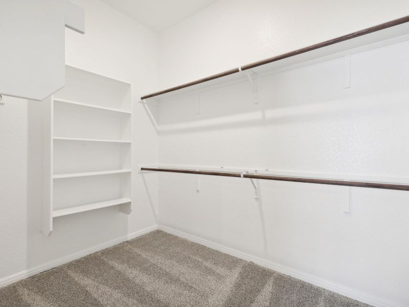 This large primary bedroom closet has lots of space for clothes and storage.