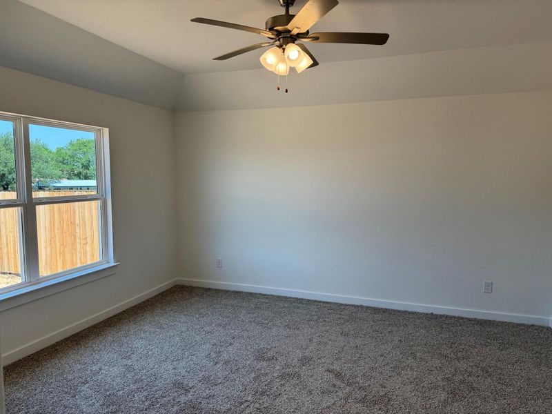 Unfurnished room with carpet floors, a ceiling fan, and vaulted ceiling Unfurnished room with carpet floors, a ceiling fan, and vaulted ceiling