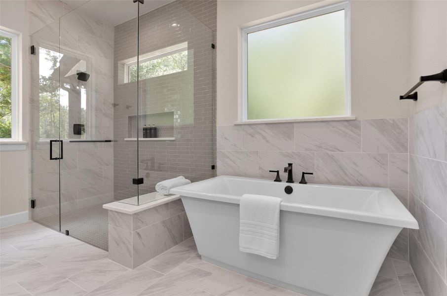 This bathroom showcaseselegant tilework includingmarble-look tile surrounding thefreestanding tub and sleeksubway tile that extends to theceiling in the walk-in showeraccented by built-in shelving andmatte black fixtures.