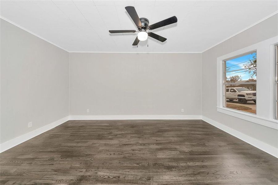 Spare room featuring ornamental molding, dark wood-type flooring, and ceiling fan Spare room featuring ornamental molding, dark wood-type flooring, and ceiling fan
