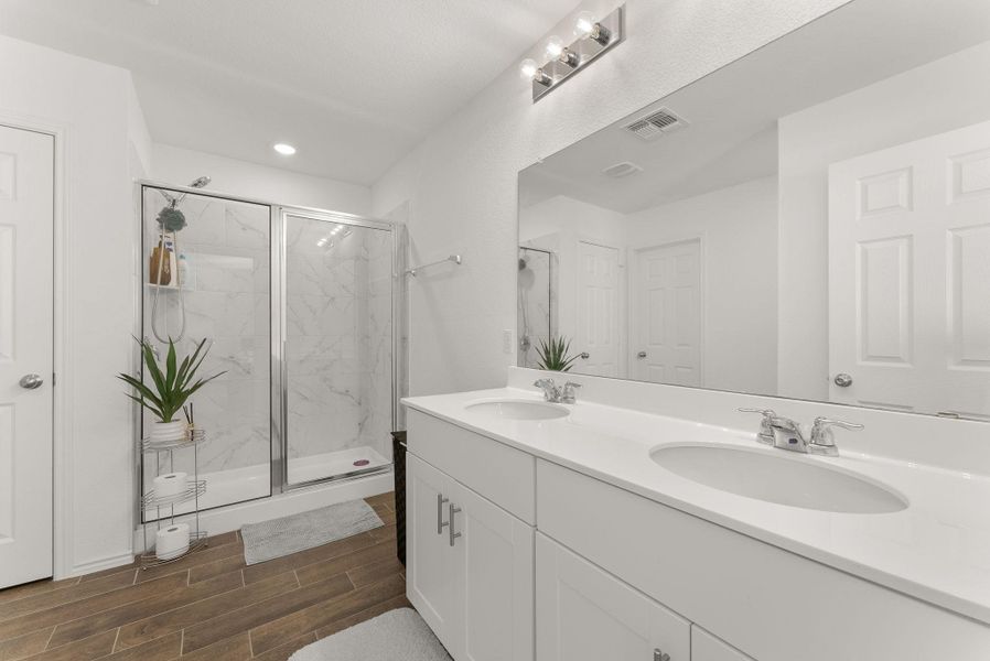 Full bathroom with visible vents, wood finish floors, a sink, and a marble finish shower