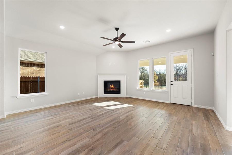 Unfurnished living room featuring light wood finished floors, a glass covered fireplace, ceiling fan, and recessed lighting Unfurnished living room featuring light wood finished floors, a glass covered fireplace, ceiling fan, and recessed lighting