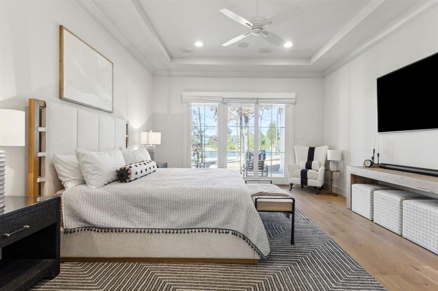 Bedroom with a tray ceiling, access to outside, recessed lighting, and wood finished floors Bedroom with a tray ceiling, access to outside, recessed lighting, and wood finished floors