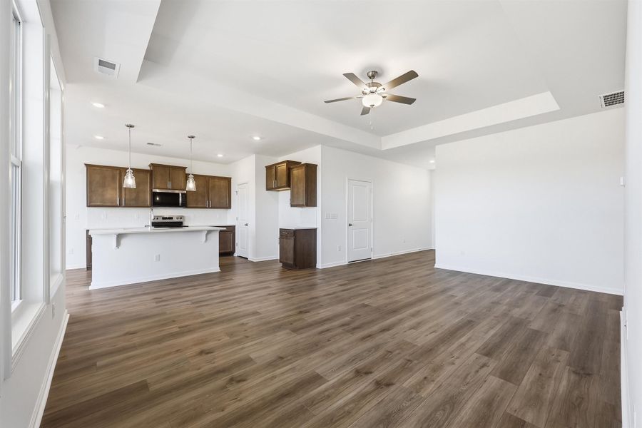 Unfurnished living room with a raised ceiling, a ceiling fan, dark wood-style flooring, and recessed lighting