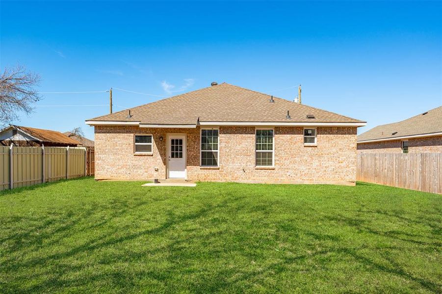 Rear view of house featuring a fenced backyard and a yard