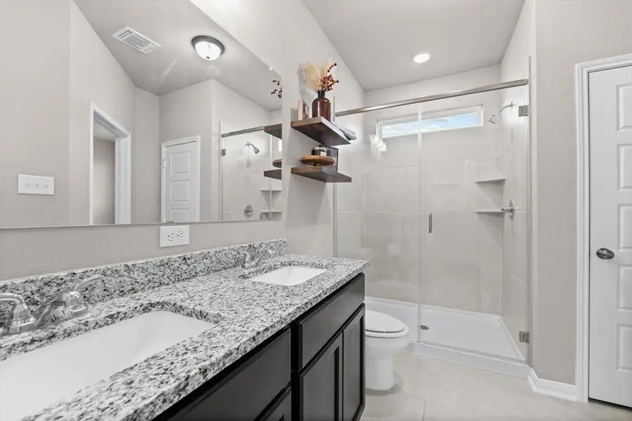 Bathroom featuring double vanity, a shower stall, and light tile patterned flooring Bathroom featuring double vanity, a shower stall, and light tile patterned flooring