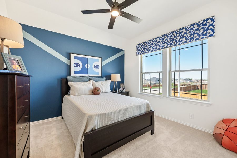 Kids bedroom with blue accent wall, ceiling fan, carpet, and double windows