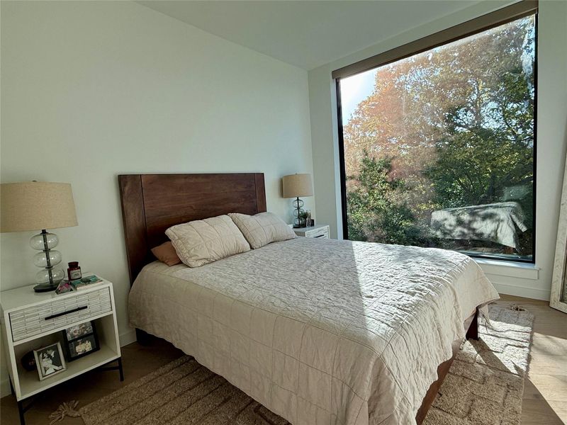 Floor-to-ceiling windows offer serene nature views from this peaceful bedroom.