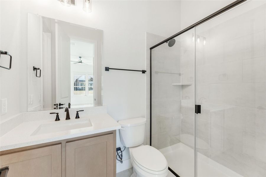 Bathroom with single vanity, white quartz countertop, glass walk-in shower, and black hardware accents