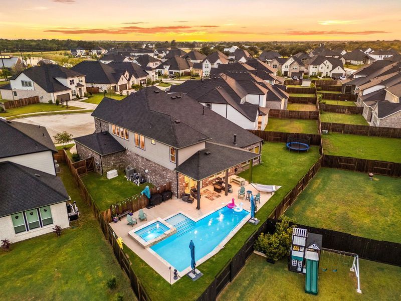 This impressive backyard offers a sparkling pool and spa, surrounded by a spacious patio perfect for outdoor living and entertaining. The covered area extends the living space outdoors, while the large fenced yard provides plenty of room to play or relax