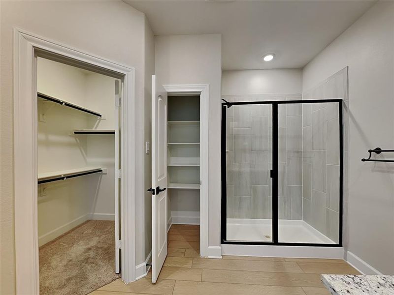 Bathroom featuring a shower with shower door and wood-type flooring