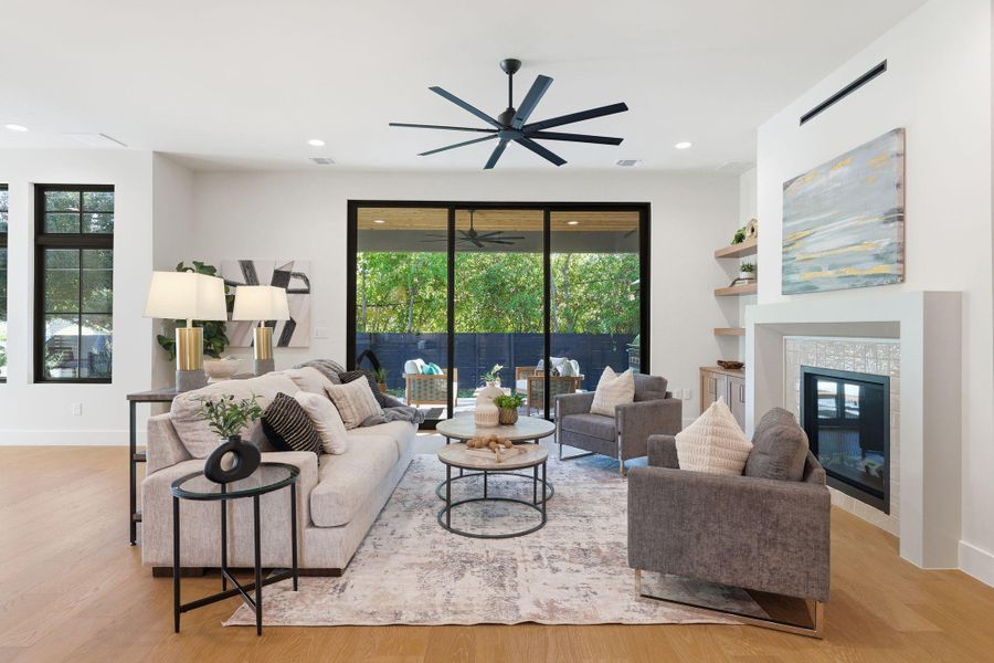 Living room with a tile fireplace, healthy amount of natural light, light wood-style flooring, recessed lighting, and built in features