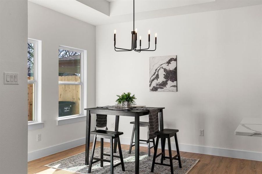 Dining area featuring a notable chandelier, wood finished floors, and baseboards