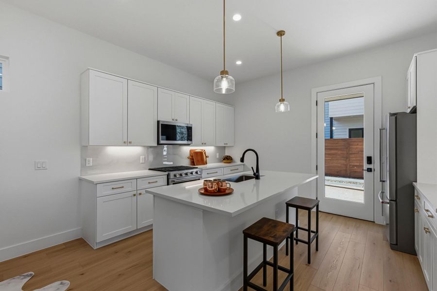 Kitchen with light wood-style flooring, white cabinetry, a breakfast bar, and pendant lighting