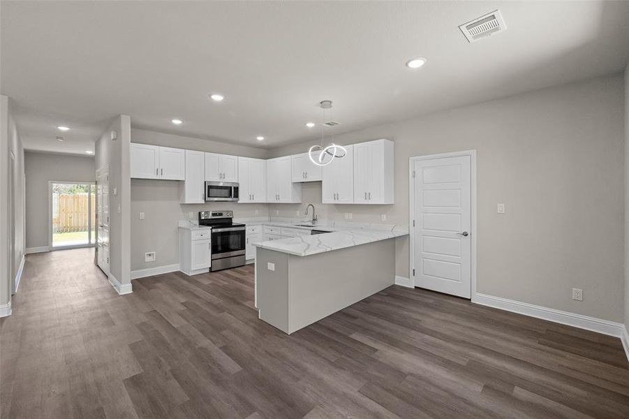 Kitchen with white cabinetry, stainless steel appliances, sink, kitchen peninsula, and dark wood-type flooring