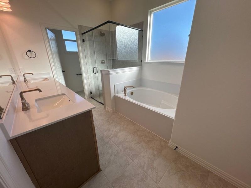 Bathroom featuring a bath, double vanity, a shower stall, and light tile patterned floors Bathroom featuring a bath, double vanity, a shower stall, and light tile patterned floors
