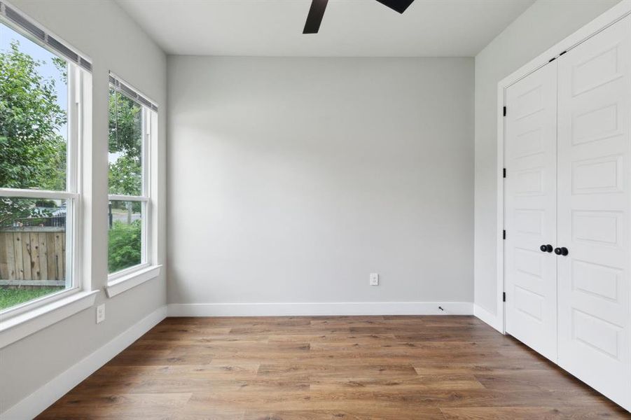 Unfurnished bedroom with multiple windows, hardwood / wood-style floors, and ceiling fan