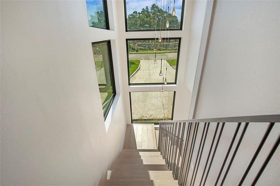 Stairway with a towering ceiling, wood-type flooring, and plenty of natural light